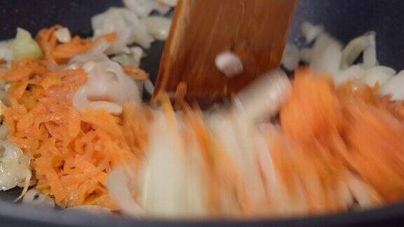 烹饪冷冻胡萝卜在平底锅里煎洋葱特写