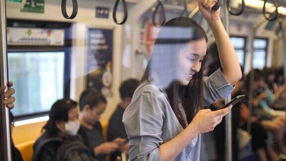 亚洲女性在坐空铁时使用智能手机慢镜头