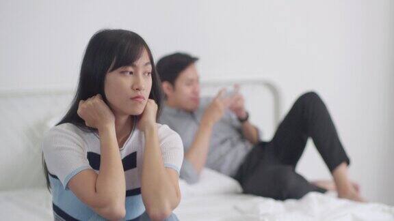 悲伤的亚洲女人坐在床上不快乐的夫妇有关系问题