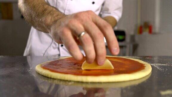 手工厨师把奶酪放在比萨的基础上番茄酱特写