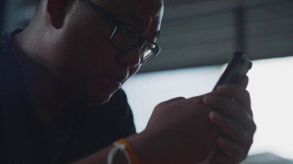 亚洲男子使用智能手机触摸屏和观看在线视频