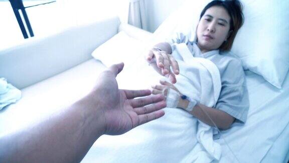 亚洲病人在床上握着家人的手