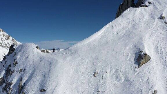 无人机拍摄的男性登山者攀登陡峭的雪山