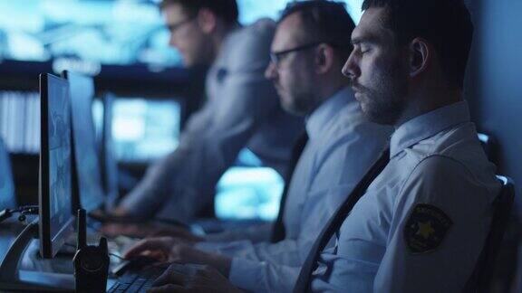 一群安全人员正在一间充满显示屏的黑暗监控室里工作