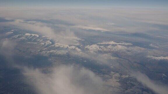 在一个多云的冬天从飞机的窗口看城市和雪山在背景中可见飞机的部分