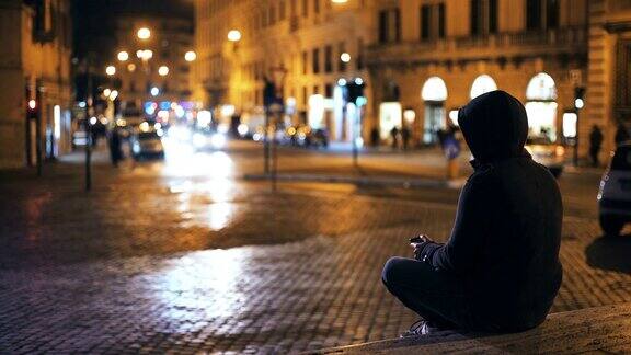 一个人晚上独自坐在台阶上使用智能手机