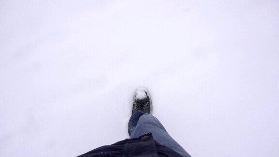 一个男人走在雪地上把腿从镜头上挪开背景冬天慢镜头