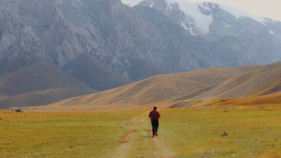一名年轻的背包客在吉尔吉斯斯坦阳光明媚的夏天在风景秀丽的山谷徒步旅行