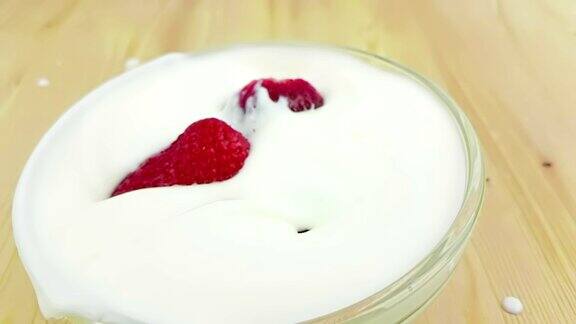 健康的草莓以慢镜头落到白色的酸奶木桌上健康食品