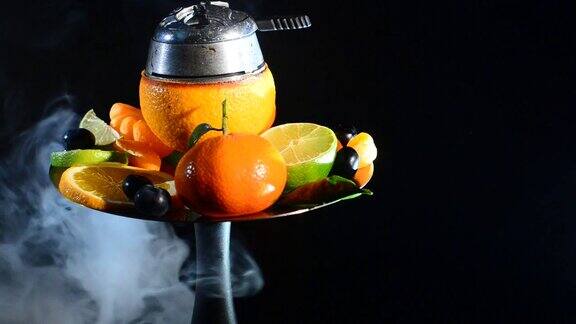 现代水果水烟碗与橙子和许多新鲜水果kaloud大量烟雾在黑色背景孤立