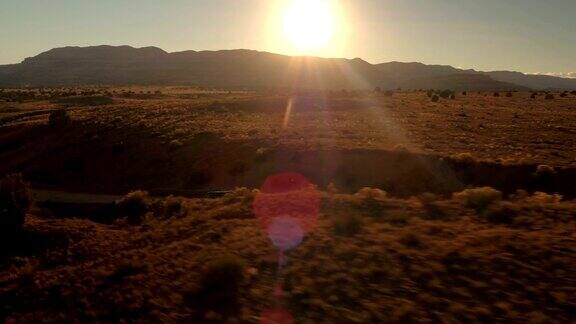 镜头:金色的夕阳下一辆黑色SUV行驶在沙漠山谷尘土飞扬的道路上