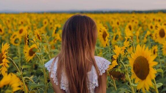 美丽的东方女孩走过鲜花盛开的草地转身微笑向日葵从后面看