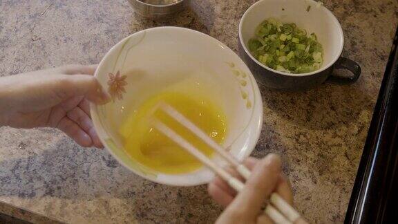 一个女人用筷子打鸡蛋准备做饭