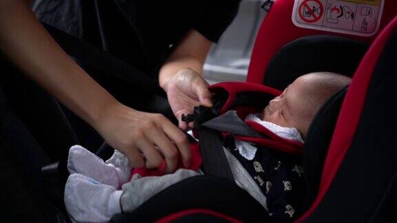 母亲在汽车安全座椅上为婴儿系安全带