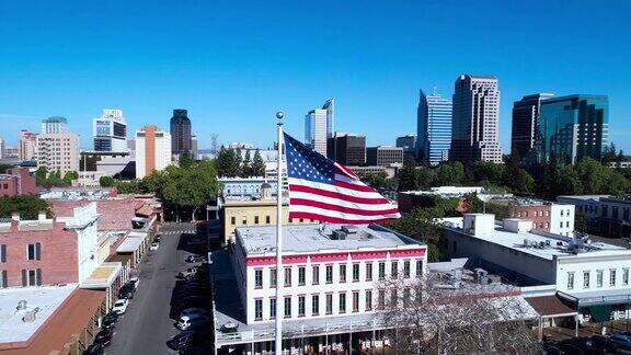 老萨克拉门托和遥远的萨克拉门托市中心前飘扬的美国国旗无人机低空视频与轨道摄像机运动