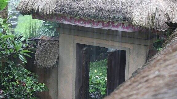 热带夏雨滴落在花园的稻草屋顶上印尼巴厘岛