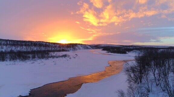 天线:蜿蜒的冰雪河流在夕阳下流过冰雪皑皑的冬季景观