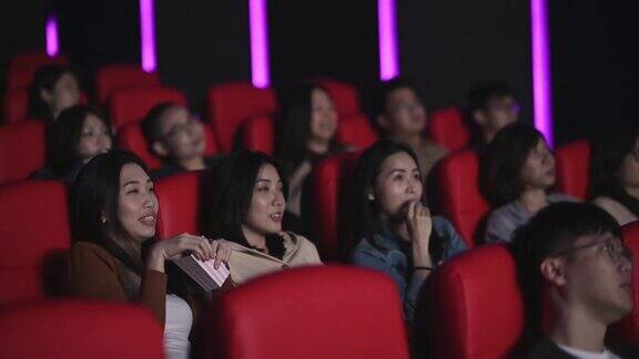 亚洲的中国女人在电影院看恐怖的惊悚电影和其他观众一起看