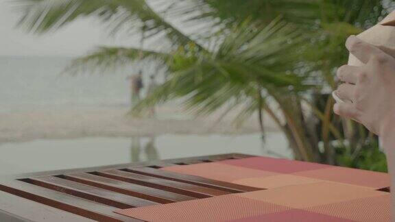 坐在沙滩上喝椰子汁的男人