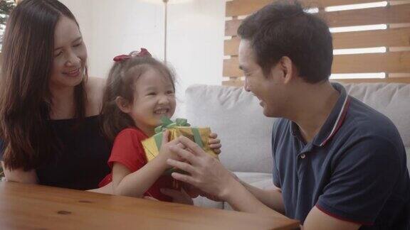 年轻的亚洲父亲给礼物盒给他的小女儿惊喜