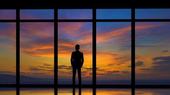 在日出的背景下站在窗边的男人时间流逝