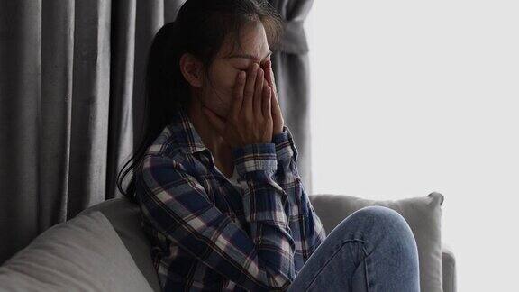 抑郁失意的亚洲年轻女性把脸藏在手里遭受精神压力、生活问题、抑郁女性、家庭问题、虐待、家庭暴力、抑郁观念和自杀