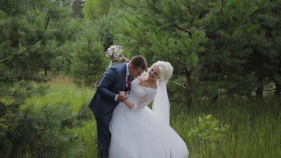 美丽的新娘和新郎在森林里牵手拥抱