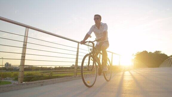 低角度:无忧无虑的小伙子在一个阳光明媚的夏日早晨骑着自行车吹着口哨