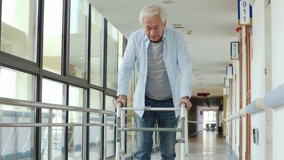 在走廊上用助行器走路的亚洲老人