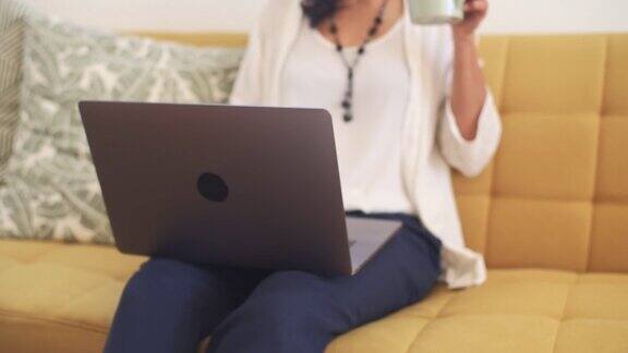 女商人一边喝咖啡一边在家里用笔记本电脑工作