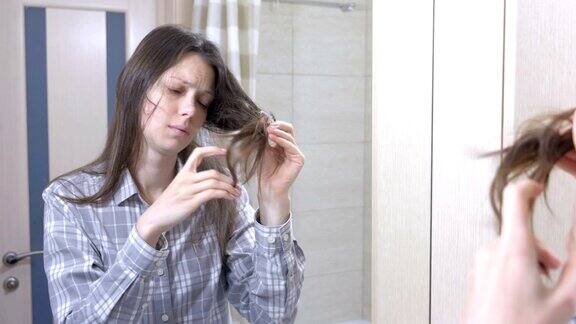 浴室里的女人看着自己干枯的头发
