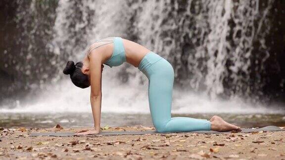 快乐女人瑜伽姿势平衡身体冥想在自然瀑布背景