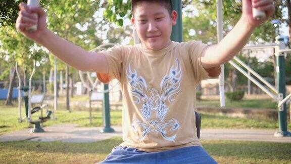 一个十几岁的亚洲男孩在公园外面做运动器材