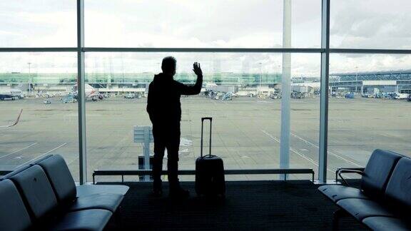 一位中年男子在机场窗口挥手道别旅行概念
