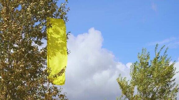 一面黄色的旗帜在强风中飘扬4K视频旗帜天空背景