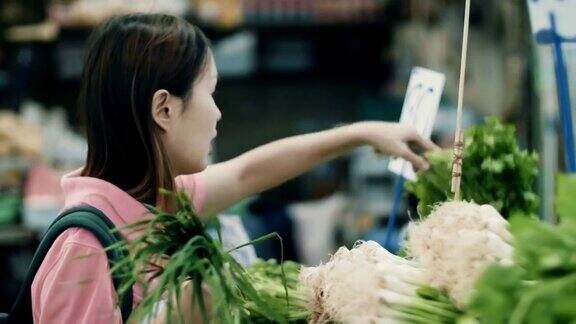 年轻女子在超市的菜区挑选蔬菜