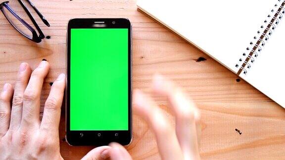 手用手机用绿色屏幕在办公室桌面上查看