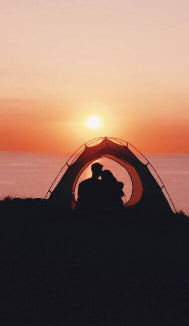 这对浪漫的情侣坐在海边的露营帐篷里