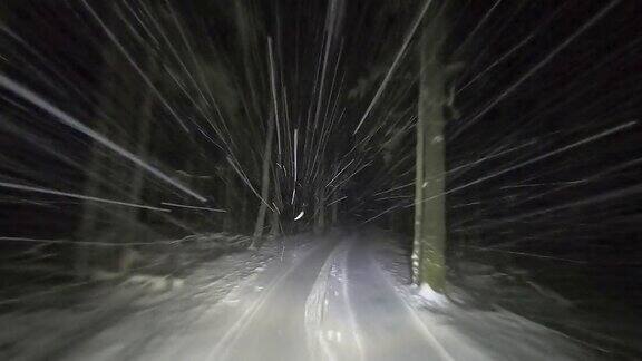 在冬天下雪的森林道路上开车大雪反射着汽车前灯的光在冬天开车旅行