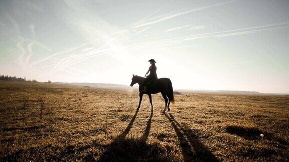 年轻女牛仔在户外慢动作棕色的马