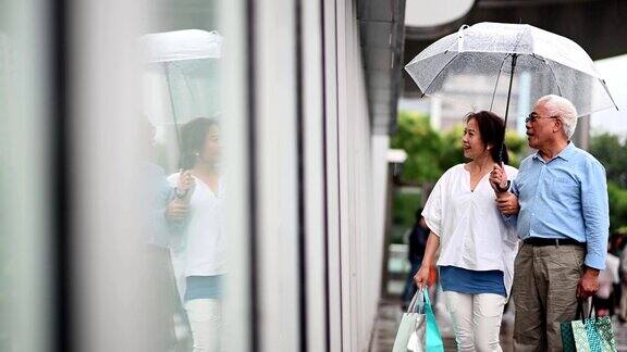 一对老年夫妇在雨季的时候逛街