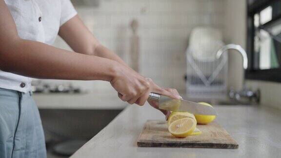 女手在厨房的砧板上用刀切黄柠檬
