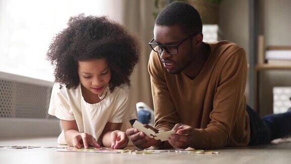 黑爸爸和黑女儿在地板上收集拼图