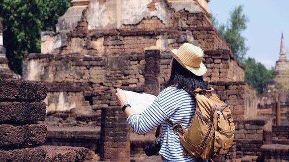 亚洲女游客在泰国素可泰古塔寺庙泰国建筑看到地图女性旅行者在休闲泰国服装风格访问城市概念