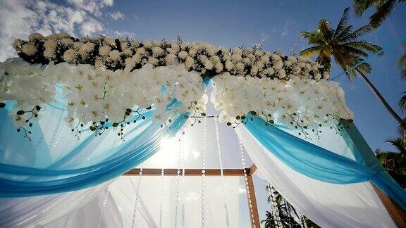 热带海滩上的婚礼拱门装饰着鲜花和大型迎风织物菲律宾保和