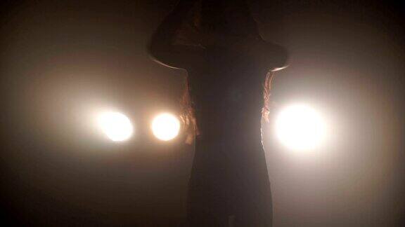 一个女孩的剪影在灯光的背景下热情地跳舞