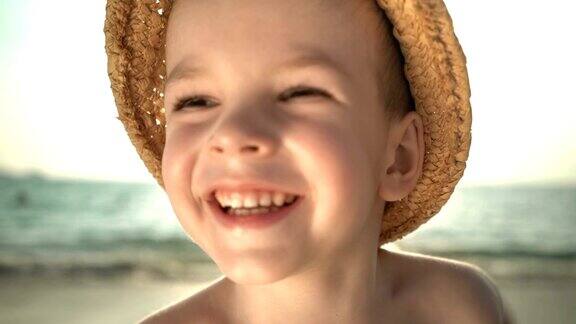 肖像可爱的男孩戴着草帽在海滩上UHD视频