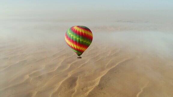 热气球在沙漠云层中飞行的鸟瞰图迪拜阿联酋