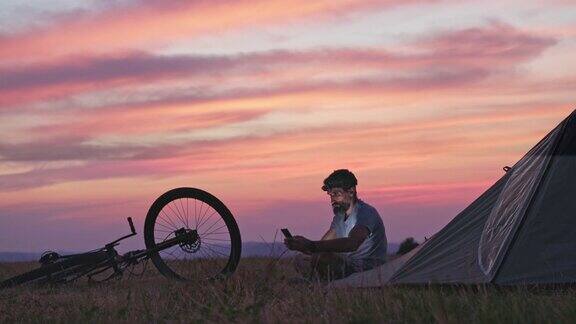 在日落时骑山地自行车和露营