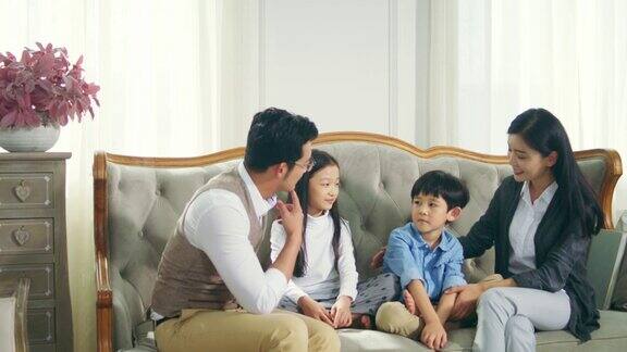 亚洲母亲和父亲在家里与儿子和女儿聊天